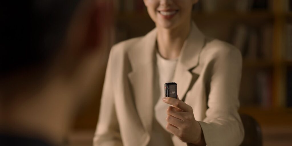 Woman holding a DJI Mic 2 (1-Channel) wireless microphone during an interview setup