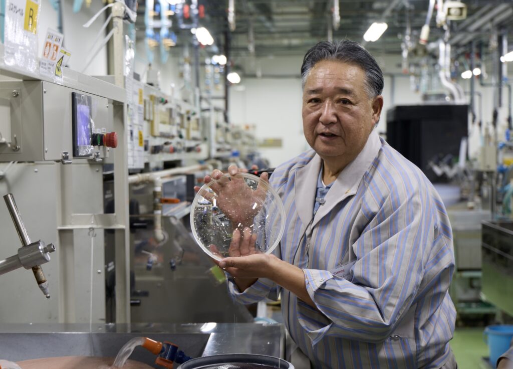 One of Canon's lens artisans holding a lens element.