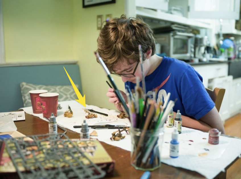 An arrow indicated where the focus was in a photo of a boy painting miniatures.