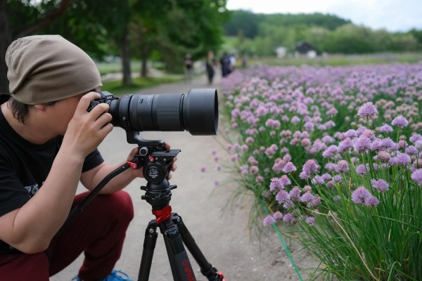 Photographer using a Tamron 150-500mm f/5-6.7 Di III VC VXD lens on a Fujifilm X-mount camera mounted on a tripod