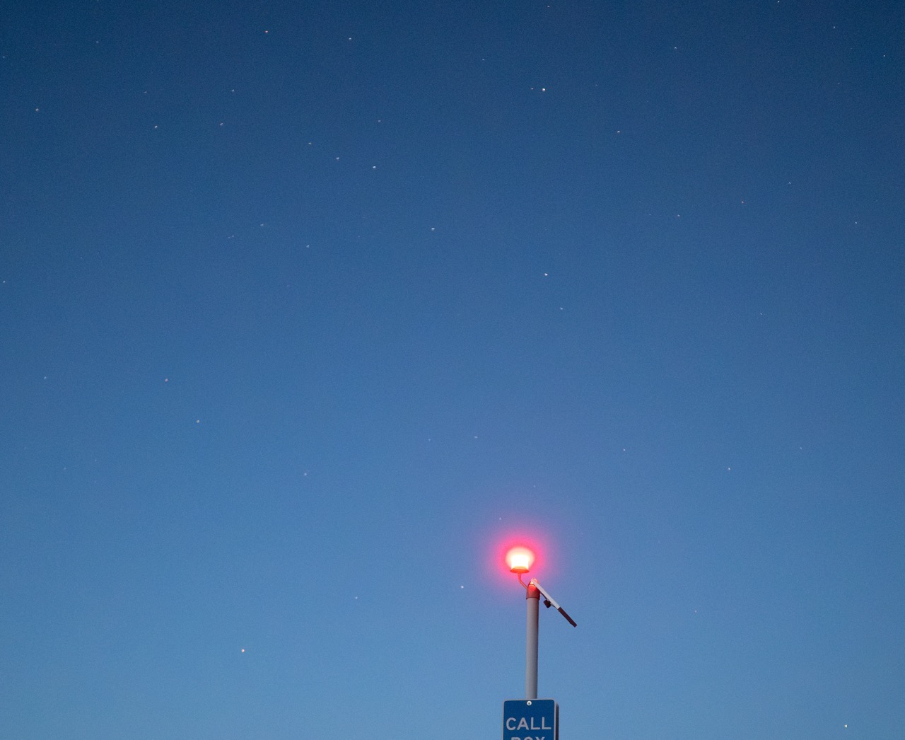 A callbox at a beach lit only wiht the light of the callbox.